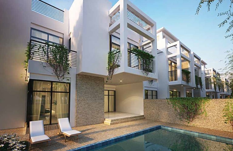 Large townhouse complex blends white and brick exteriors with ivy adornments. The backyard, featuring a pool, is completed with two beach chairs. 