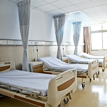 Clean and bright, well-organized hospital room with multiple beds displayed horizontally and medical equipment.