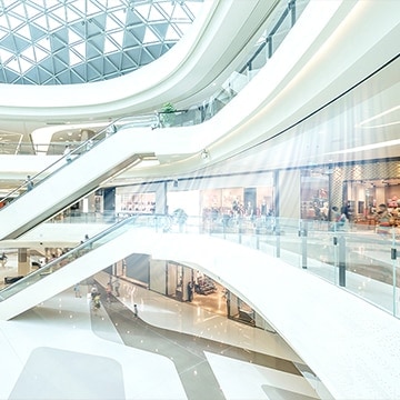 Captures a large, airy shopping mall with expansive walkways and modern architecture. The design focuses on providing a luxurious and spacious shopping experience.
