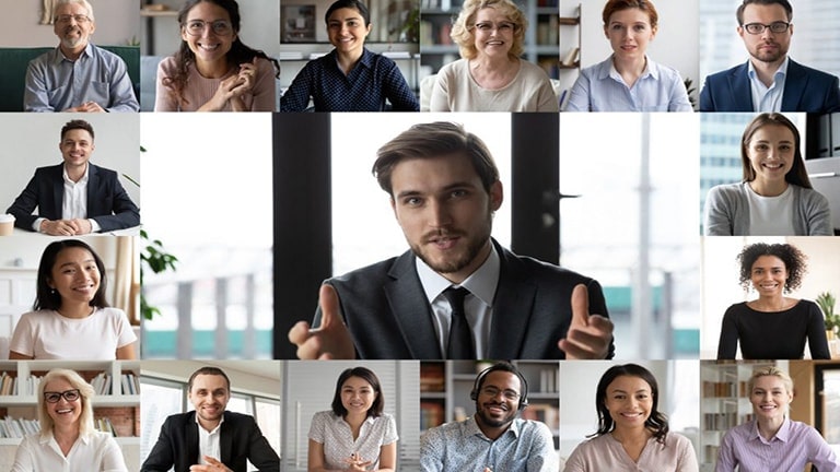 Collage of 17 people from an online conference. Center features a man in a suit speaking, zoomed in larger than others.