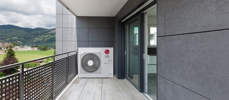 A gray tiled balcony with a checkered fence showcases a central LG Multi V S outdoor unit. Mountains and green fields are visible on the left.