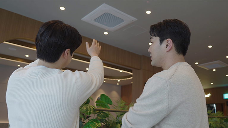 Two men are talking while looking at the air conditioner.