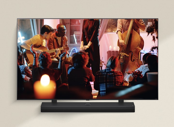 A cozy concert in a living room is playing on the screen. The WOW Interface menu appears as an overlay and the user navigates to soundbar settings.