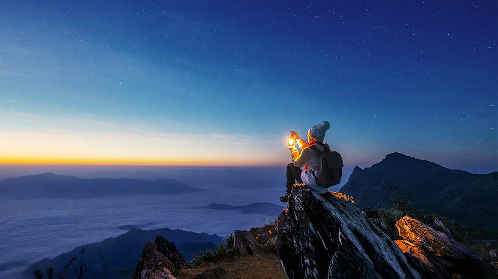 A video showing a woman perched on the edge of a mountain. A straight line across the screen transforms into a wave, representing the tone curve that refines the picture.