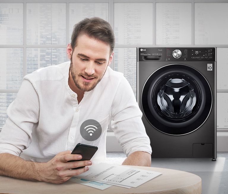 A man is monitoring the condition of the washing machine through a mobile phone app.