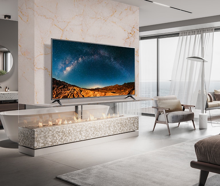 W prostej sypialni z widokiem na morze na półce ściennej stoi telewizor. Błękitna sceneria morska wygląda jasno i wyraźnie na ekranie telewizora.