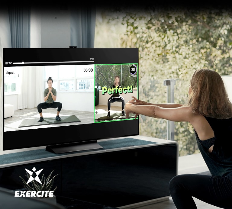 Kobieta wykonuje przysiady podczas oglądania telewizji. Na ekranie telewizora widać graficzne instrukcje wykonywania ćwiczeń i utrzymywania postury.