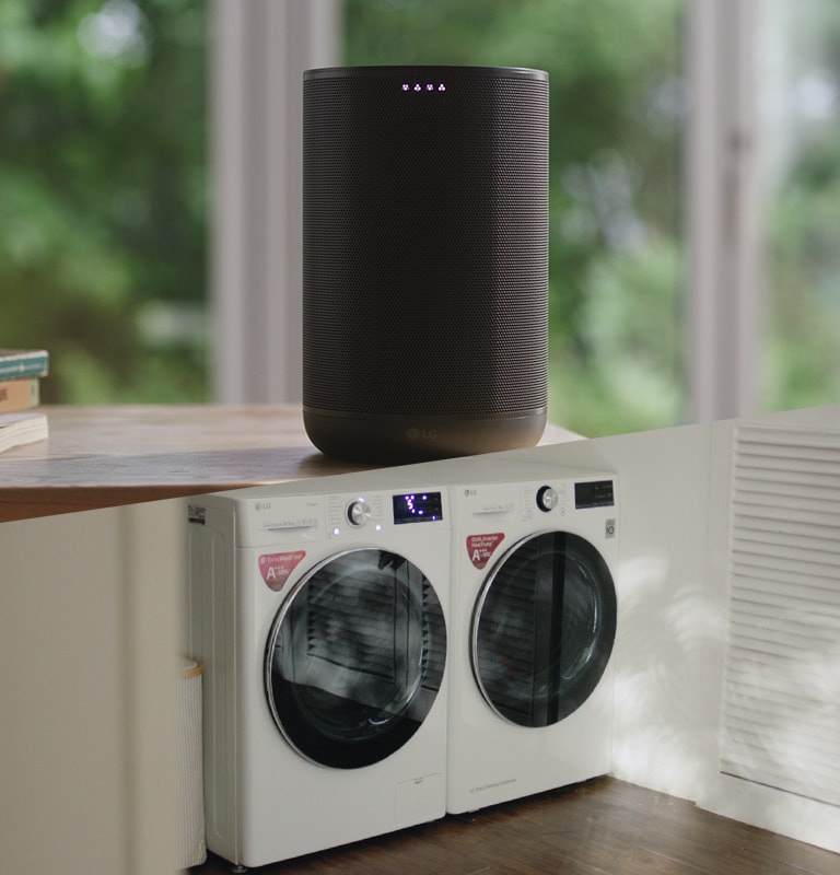 Ikona odtwarzania/wstrzymania na dole ekranu nad trzema kropkami. Druga kropka jest wyróżniona na znak, że to jest drugi z trzech filmów w karuzeli. W pierwszej scenie filmu zdziwiona kobieta podchodzi do kanapy, na której siedzi jej mąż. Mąż mówi coś, co ją uspokaja. Znajdujący się w pobliżu głośnik AI słucha ich poleceń, po czym na ujęciu pojawia się pralnia, w której stoją pralka i suszarka LG.