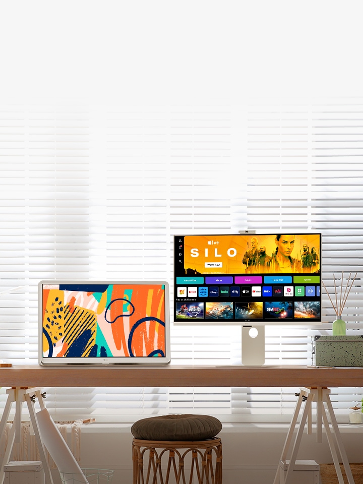 Jasna scena w salonie przedstawia inteligentny monitor i telewizor LG z funkcją Room&TV umieszczone na stoliku przy oknie.