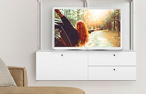Telewizor LG z funkcją Room&TV doskonale komponuje się z wystrojem wnętrza na półce w salonie, obok innych stylowych produktów do domu.