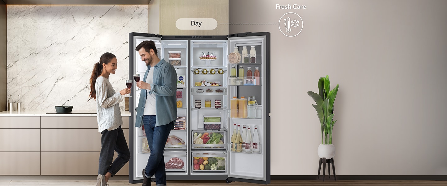 On the left side, The refrigerator is open and the couple is standing near the refrigerator.