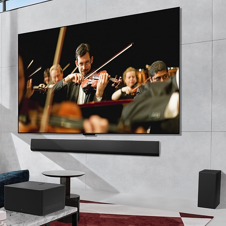 Uma TV LG OLED com orquestra no ecrã montado contra uma parede e uma Zero Connect Box colocada à frente.