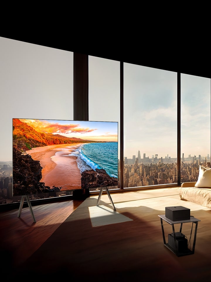 Il TV LG SIGNATURE OLED M4 sul piedistallo davanti a una finestra che arriva fino al soffitto in un appartamento moderno illuminato dal sole.