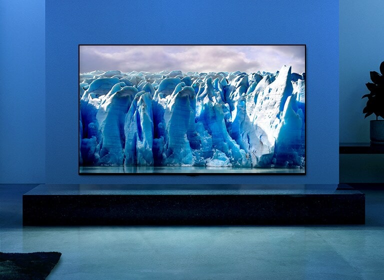 O vídeo mostra uma imagem ampliada do iceberg e há um efeito visual de um circuito azul a passar sobre a imagem do iceberg. A cena muda para mostrar uma TV pendurada numa sala de estar com luz e fundo azul. Um vasto iceberg no ecrã da TV.
