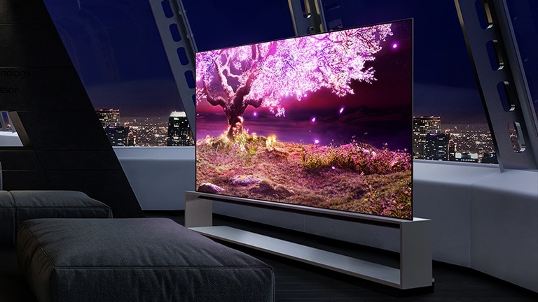 Televisão com uma árvore cor-de-rosa brilhante numa sala escura à noite.