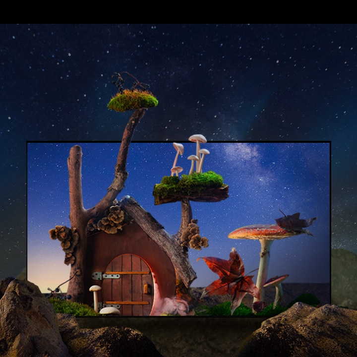 Uma casinha de aparência fantástica, com árvores, cogumelos e grandes rochas, está sob o céu noturno estrelado.