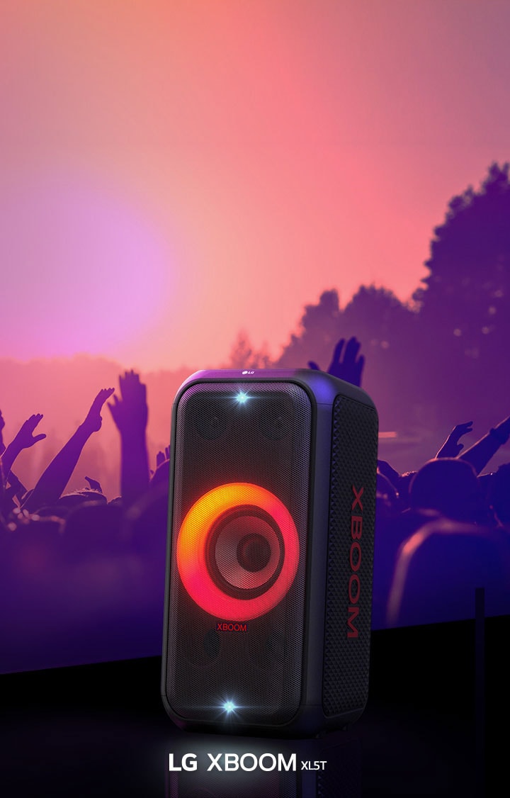 LG XBOOM XL5T is placed on the stage with red-orange gradient lighting is on. Behind the stage, people enjoy the music.