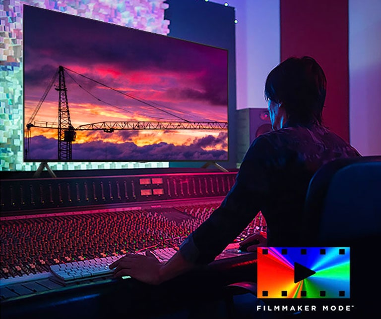 A man in a dark editing studio looking at an LG TV displaying the sunset. On the right bottom of the image is a FILMMAKER Mode logo.	