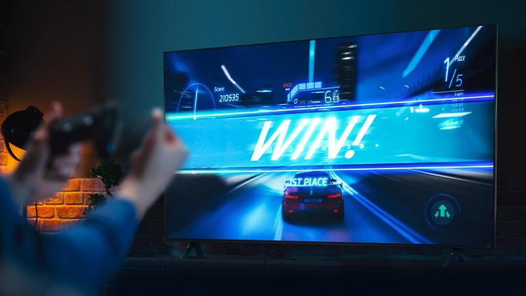 A car racing game on the finish line, with the sign saying 'WIN!', as the player clenches on to the game joystick. ALLM, eARC, HGiG logo are placed on the bottom left corner.