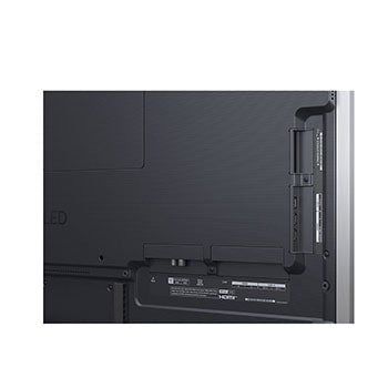 Stor vy över ett vardagsrum i ett lyxhem där en man tittar på en film på sin väggmonterade LG OLED TV. Tv:ns design smälter elegant in i väggen och inredningen.