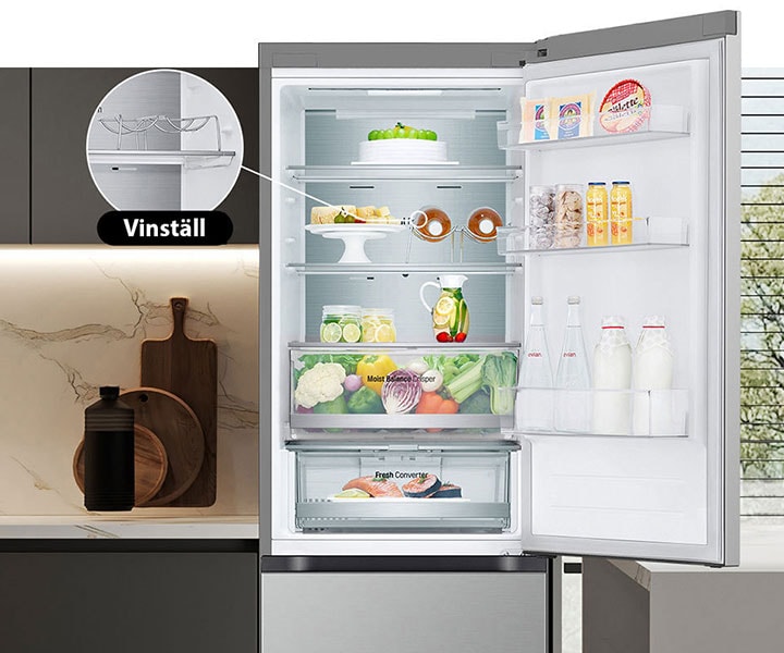 Ett kylskåp fullt med färsk mat med dörren öppen som visar vinställ och vikbar hylla.