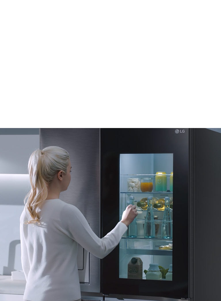 A video shows a woman approach her InstaView refrigerator and knock twice. The interior lights up and she can see the contents of her fridge without opening the door.