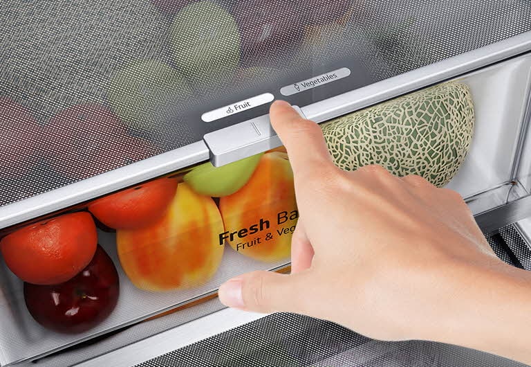 The bottom drawers of the fridge are filled with colorful fresh produce. An inset image magnifies the control lever to choose the optimal humidity level to keep produce fresh.