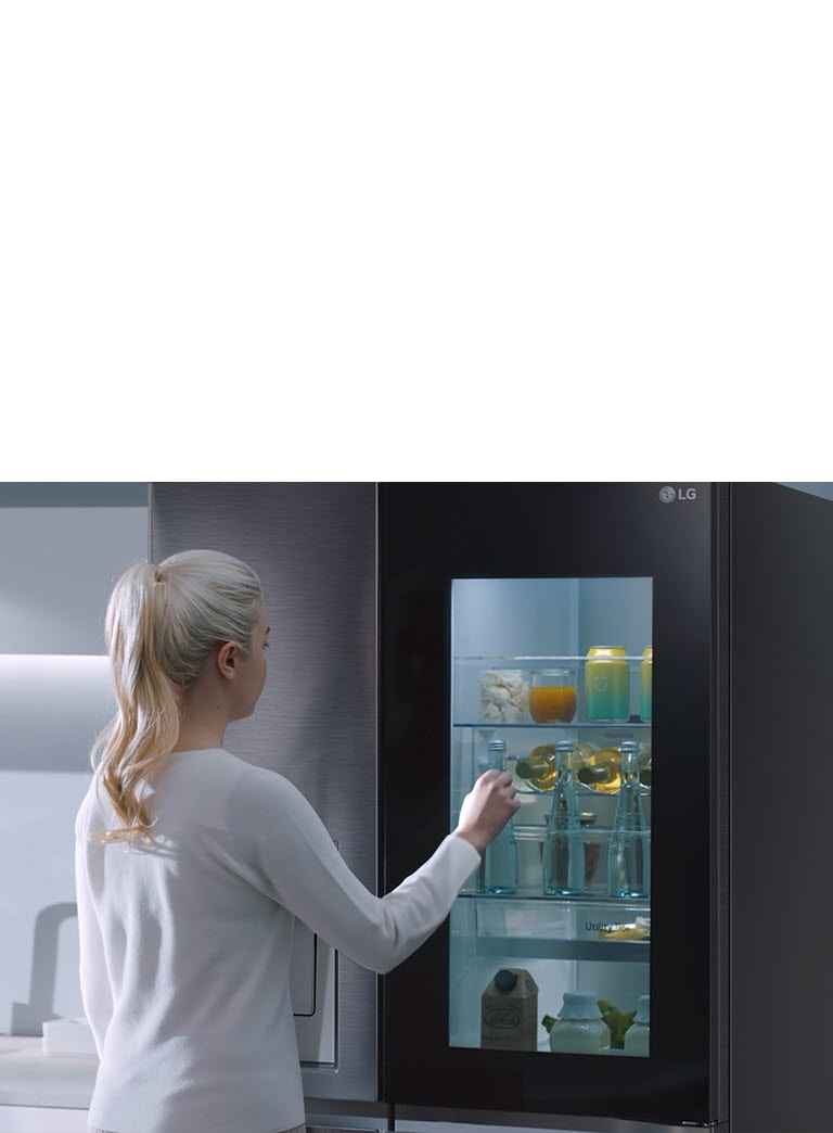 A video shows a woman approach her InstaView refrigerator and knock twice. The interior lights up and she can see the contents of her fridge without opening the door.