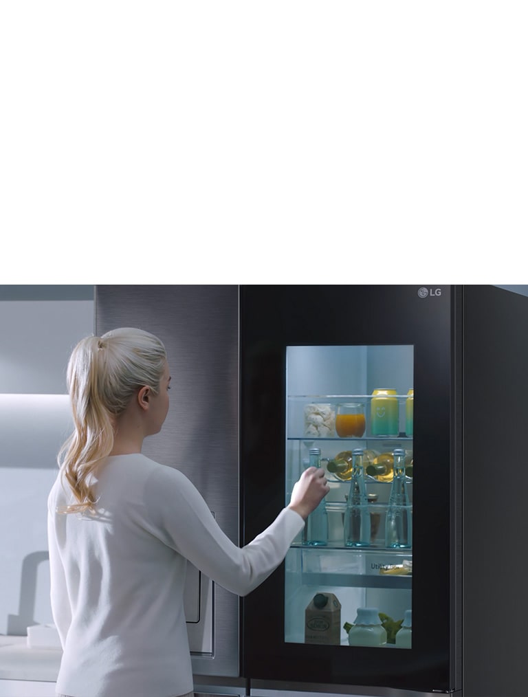 A video shows a woman approach her InstaView refrigerator and knock twice. The interior lights up and she can see the contents of her fridge without opening the door.