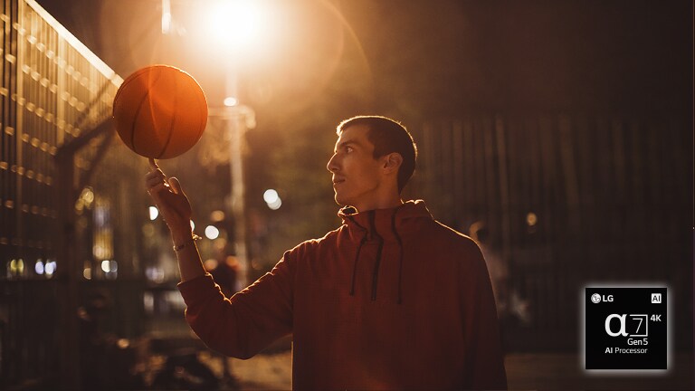 En man på en basketplan på natten snurrar en basketboll på fingret.