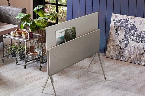 Posé sedd bakifrån med naturtidningar placerade på mediahyllan i ett vardagsrum med växttema.