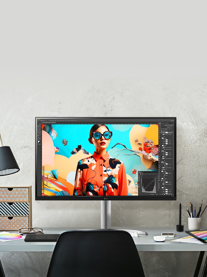 På ett skrivbord i en designstudio syns en UltraFine-skärm, med en skärm som visar pågående arbete i Photoshop.