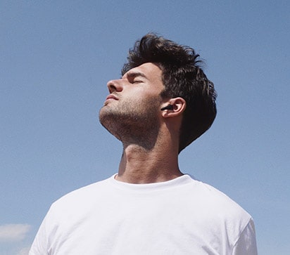 A man looking at the sky while wearing the earbuds