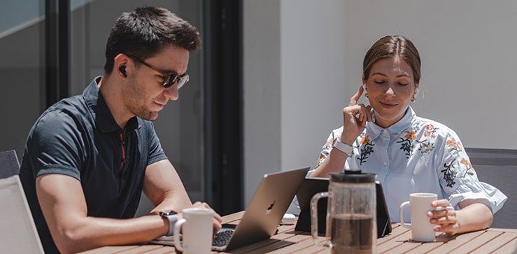 A man and a woman wearing the earbuds out at  a terrace