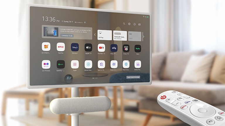 The LG XT7S speaker is attached on the LG StanbyME in the living room. The screen displays the home screen. On the bottom-right corner of the image, LG magic remote is shown.