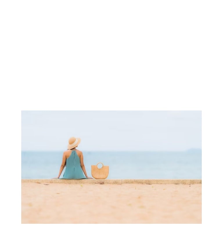 ผู้หญิงนั่งเล่นริมชายหาด