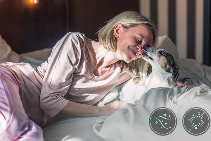 A woman and a dog are lying in bed