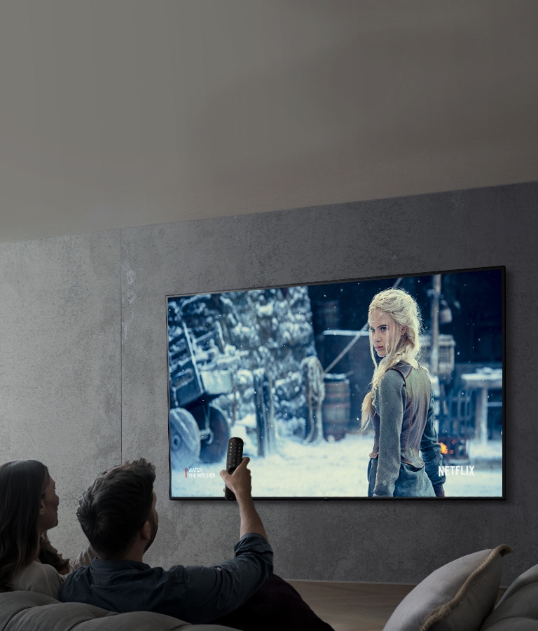 ภาพแสดงคู่รักที่กำลังดูรายการทีวีโดยใช้ทีวี LG UHD