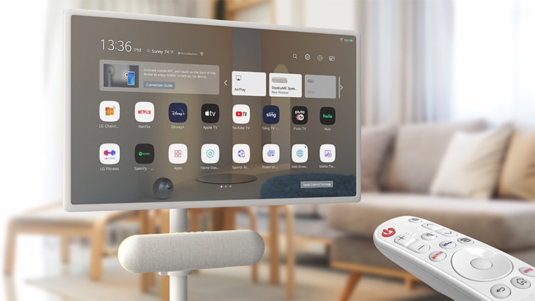 Oturma odasında LG StanbyME’ye bağlı LG XT7S hoparlör. Ekranda ana ekran görüntüsü. Görüntünün sağ alt köşesinde LG magic remote gösteriliyor.