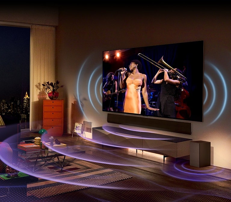 Rahat bir oturma odasında duvara monte edilmiş geniş bir TV ve soundbar yer alıyor. TV'nin her iki tarafında ve soundbar'ın altında, ses ile geniş ve görkemli bir şekilde yayılan dalga şeklinde bir grafik tasarımı bulunmaktadır.