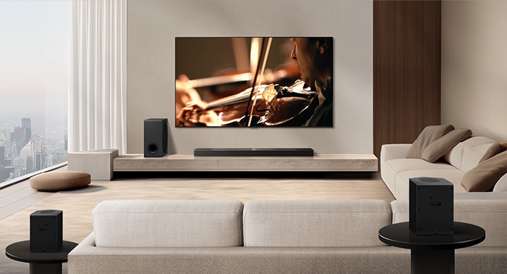 LG TV, LG Soundbar, woofer ve arka hoparlörler modern bir apartman dairesinde. Arka plan karartılır ve LG TV'den gelen görüntünün üzerinde, bir alan taranması gibi ızgara kaplaması belirir. Arka hoparlörden bir noktalı çizgi uzanarak doğrusal olarak iki arka hoparlörü gösterir. Beyaz ses boncukları bir araya gelerek dalgalar oluşturarak odayı sesle dolduruyor.