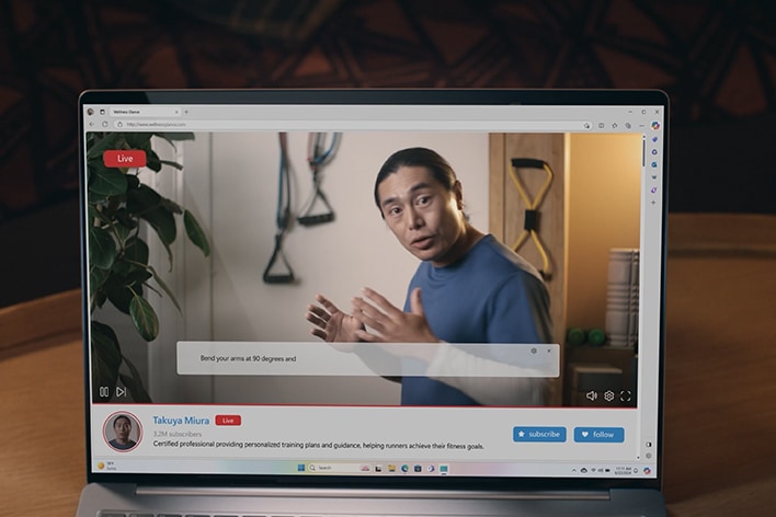 筆記型電腦螢幕上顯示著一場現場直播，畫面中有一位男士正在講話。當他講話時，螢幕底部會出現自動翻譯的字幕。