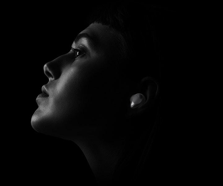 The black and white image shows a woman enjoying her music with the LG TONE Free T90S.