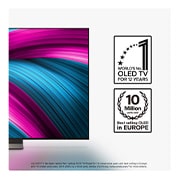 Living room space with a wall-mounted LG OLED TV. On the TV is a mountain range against a dark evening sky filled with stars. This scene is split in half. One side shows a duller, grayer version of the landscape labeled, Non Perfect Black display. On the other side is a more pleasing picture with a larger dynamic range of blacks and whites.