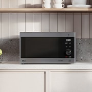 MH6565CPS Grill Microwave Sitting on Beige Countertop and Neutral light and wooden background