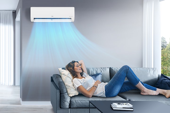 A woman resting on a sofa in the cool breeze of the air conditioner