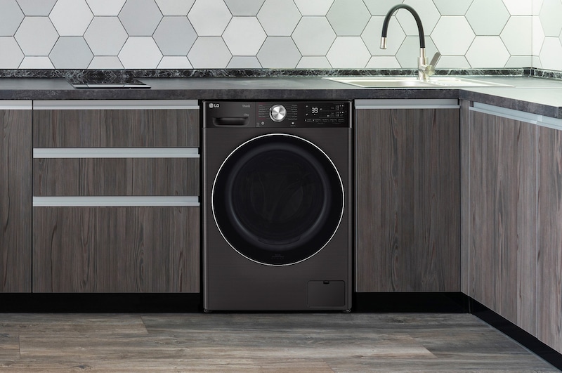The Platinum Black LG 13kg washing machine F4Y913BCTA1, shown neatly installed under a counter in a modern kitchen.