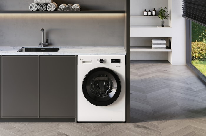 The LG 9kg washing machine F4X1009NWK in Essence White, shown built-under a counter in a modern laundry room.