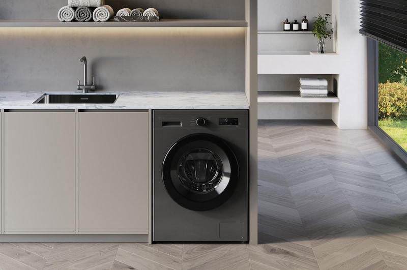 The LG 9kg washing machine F4X1009NMK in Dark Stone, shown built-under a counter in a modern laundry room.