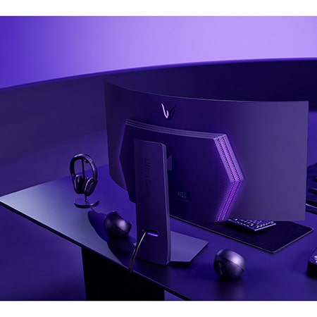 LG UltraGear Gaming Monitor 45GS95QE-B placed in an immersive gaming setup with ambient violet lighting, where the curved rear panel and RGB accents harmonize with the gaming gear.